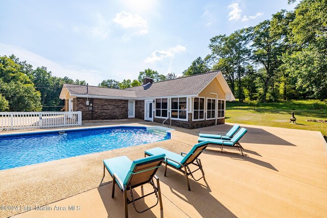 view of pool featuring a yard, a patio area, and a sunroom