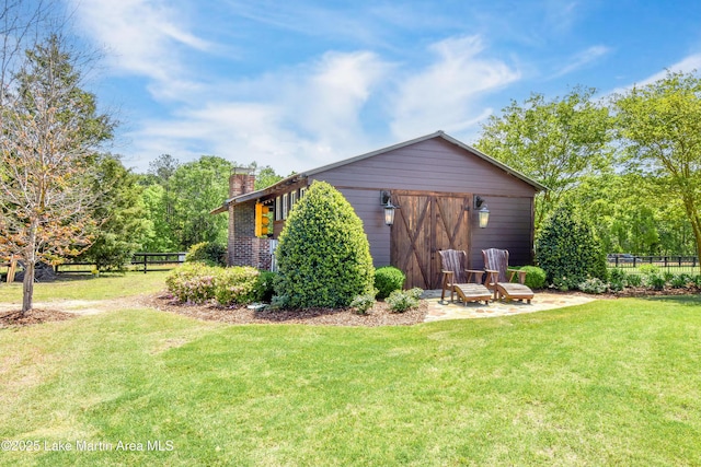 exterior space featuring fence, a garage, a lawn, and a chimney