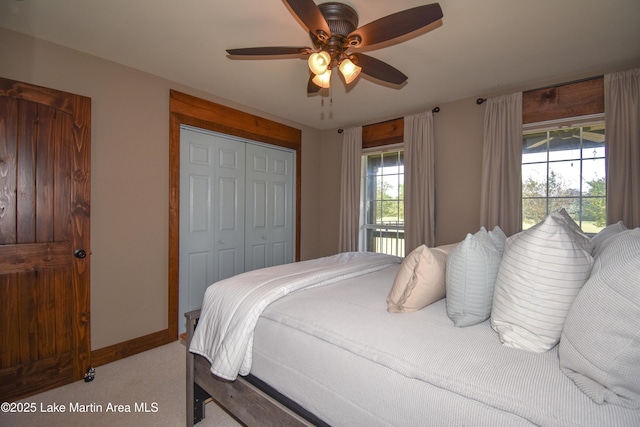 carpeted bedroom with a closet, baseboards, and a ceiling fan