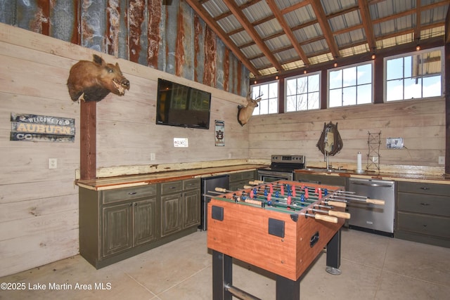 rec room with wooden walls, light tile patterned floors, and a towering ceiling