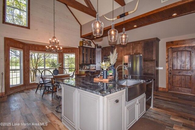 kitchen with beamed ceiling, an inviting chandelier, dark wood-type flooring, a sink, and stainless steel fridge