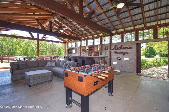 recreation room featuring high vaulted ceiling, concrete flooring, a ceiling fan, and a wealth of natural light
