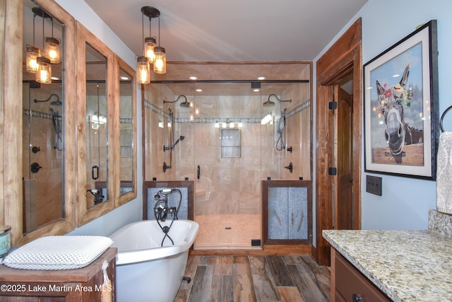 bathroom with a shower stall, a freestanding bath, wood finished floors, and vanity