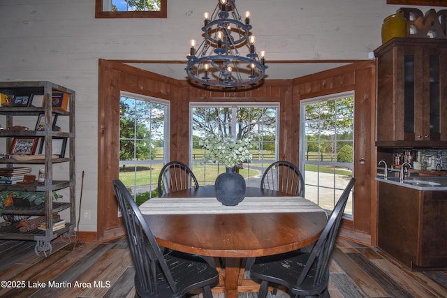 dining area with wood walls, a chandelier, and wood finished floors