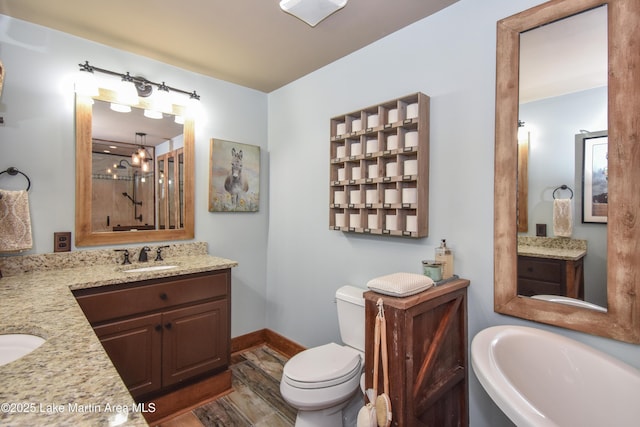 bathroom with a sink, toilet, two vanities, and baseboards