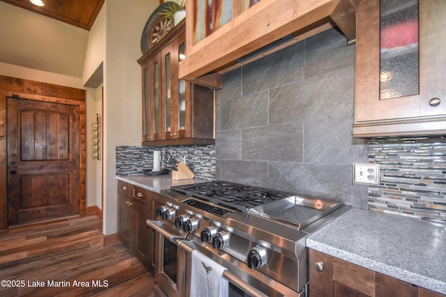 kitchen featuring dark wood-type flooring, glass insert cabinets, range with two ovens, and decorative backsplash