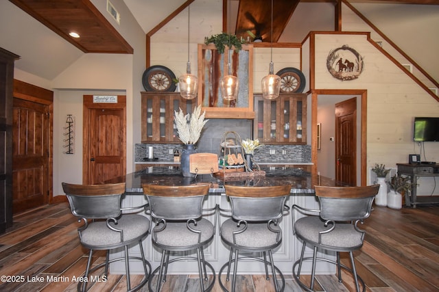kitchen with dark wood-style flooring, decorative backsplash, dark countertops, and vaulted ceiling