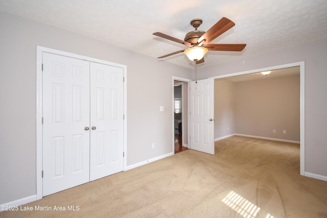 unfurnished bedroom featuring baseboards, a ceiling fan, carpet, a textured ceiling, and a closet