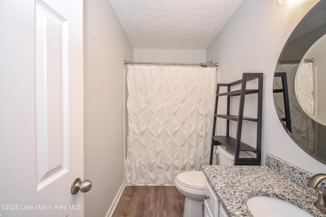 full bathroom featuring a textured ceiling, toilet, wood finished floors, vanity, and baseboards