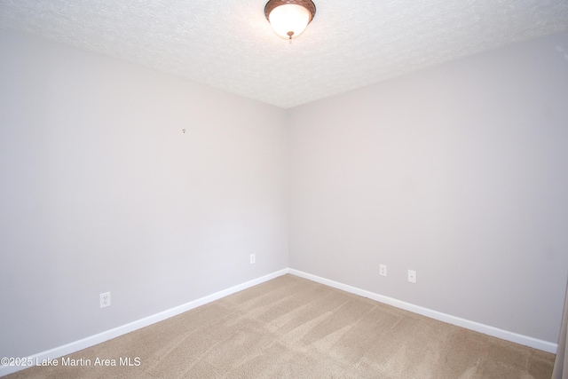 carpeted spare room featuring a textured ceiling and baseboards