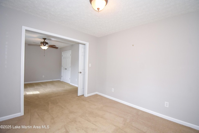 empty room with light carpet, a textured ceiling, and baseboards