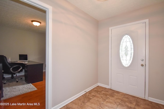 entrance foyer with light tile patterned floors, baseboards, and a textured ceiling