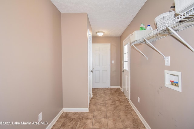 laundry area featuring laundry area, light tile patterned floors, baseboards, a textured ceiling, and washer hookup