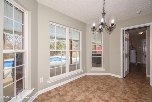 unfurnished dining area featuring an inviting chandelier, baseboards, a textured ceiling, and tile patterned floors