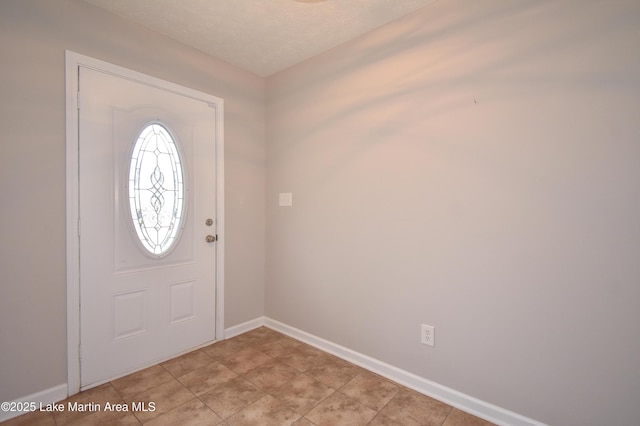 foyer entrance featuring light tile patterned flooring and baseboards