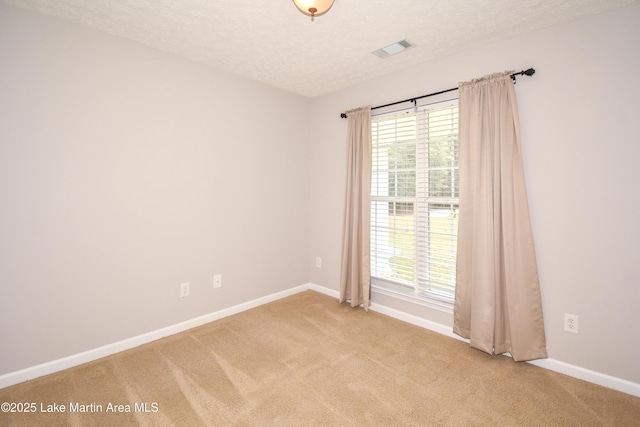 carpeted empty room with a textured ceiling, visible vents, and baseboards