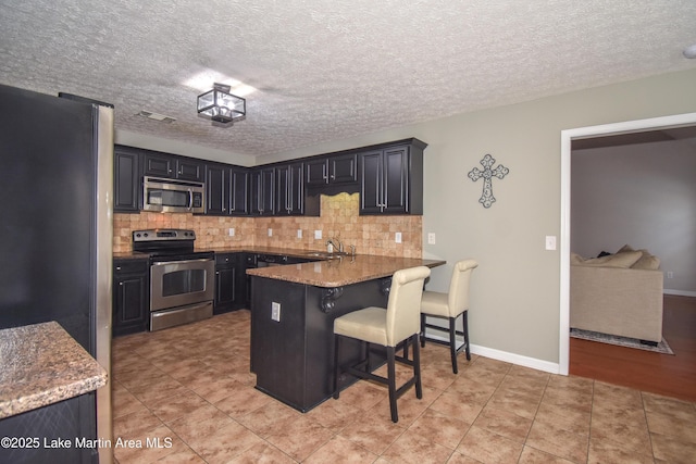 kitchen with a peninsula, tasteful backsplash, visible vents, and stainless steel appliances