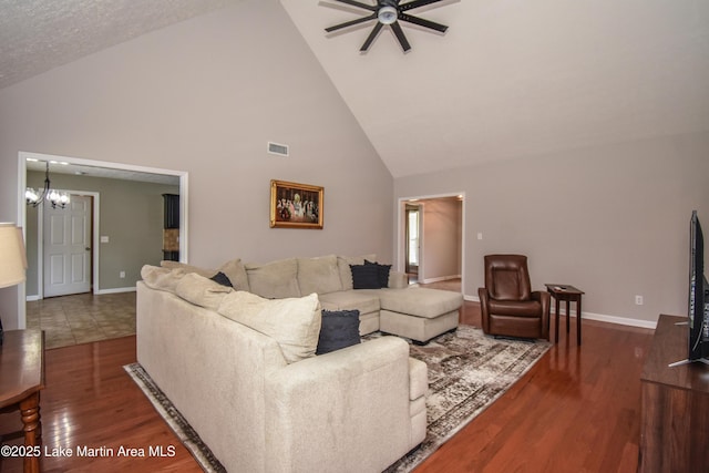 living area featuring ceiling fan with notable chandelier, visible vents, baseboards, and wood finished floors