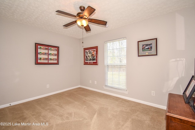 carpeted empty room with a ceiling fan, a textured ceiling, and baseboards