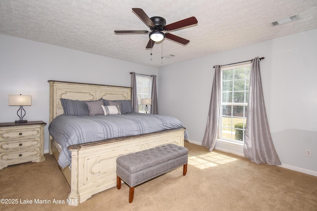 bedroom with a textured ceiling, baseboards, visible vents, and light colored carpet