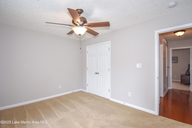 unfurnished bedroom with a closet, light colored carpet, a textured ceiling, and baseboards