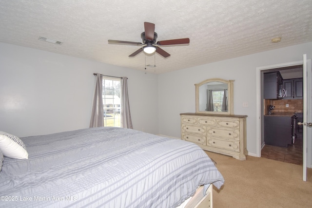 bedroom with ceiling fan, visible vents, a textured ceiling, and light colored carpet