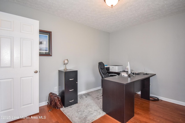 home office with a textured ceiling, baseboards, and wood finished floors