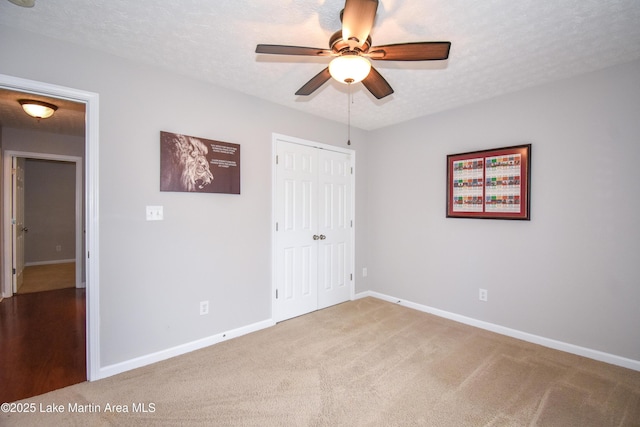 unfurnished bedroom featuring carpet floors, a closet, a ceiling fan, a textured ceiling, and baseboards