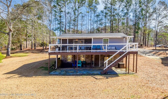 rear view of house with a wooden deck and a lawn