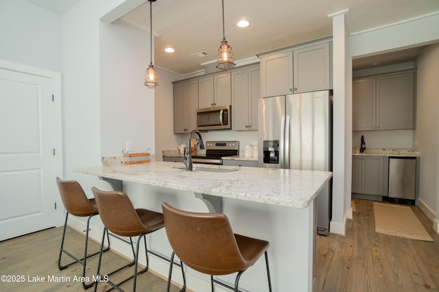 153 Whisper Trce, Tallassee, AL 36078 - kitchen with stainless steel appliances, gray cabinetry, light wood-style flooring, a kitchen breakfast bar, and recessed lighting