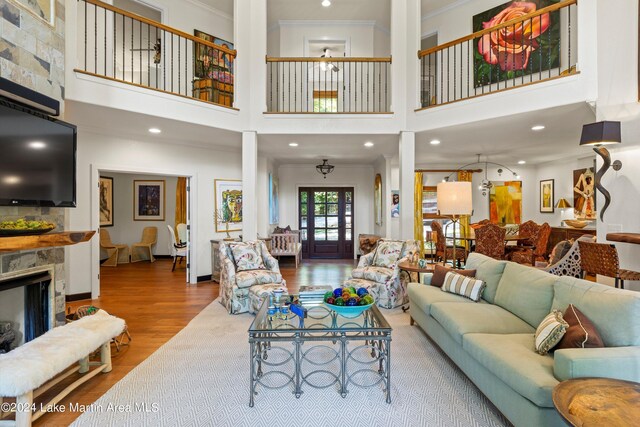 living room with wood-type flooring, a towering ceiling, and crown molding