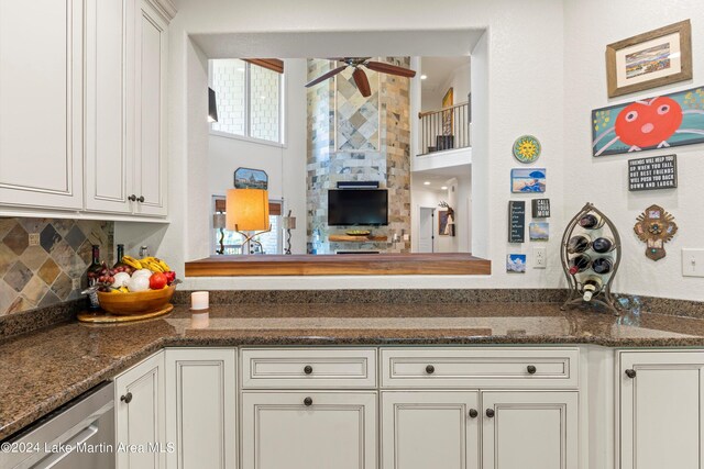 kitchen with tasteful backsplash, ceiling fan, dark stone counters, and white cabinets