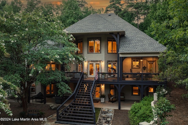 back house at dusk featuring french doors, a deck, and a patio area