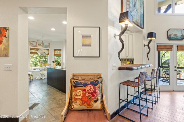 hall featuring ornamental molding, a healthy amount of sunlight, and french doors