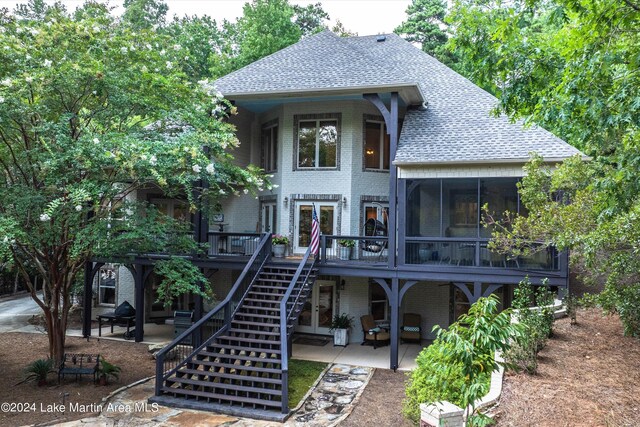 rear view of property with a sunroom, a patio, and a deck