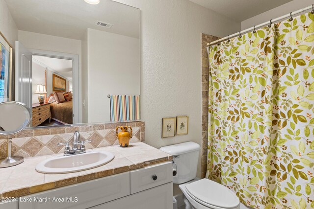 bathroom featuring tasteful backsplash, vanity, and toilet