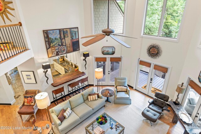 living room featuring hardwood / wood-style flooring, a towering ceiling, ceiling fan, and french doors