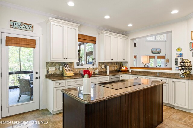 kitchen featuring white cabinetry, decorative backsplash, dark stone counters, ornamental molding, and black cooktop