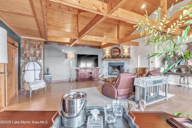 living room featuring wood ceiling, a stone fireplace, hardwood / wood-style floors, and vaulted ceiling with beams