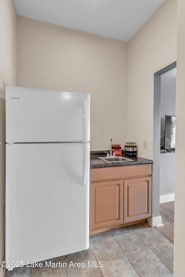 kitchen with light brown cabinetry, sink, and white refrigerator