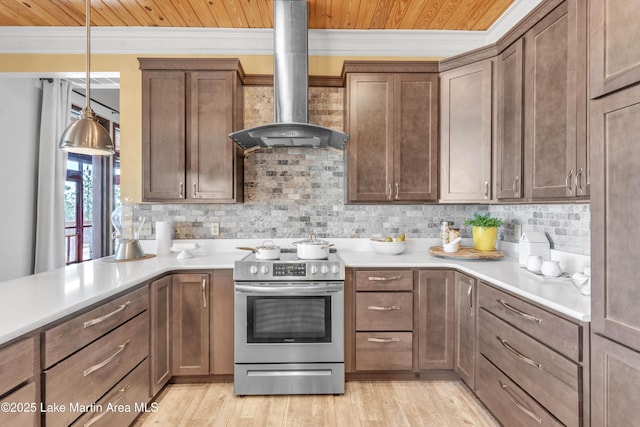 kitchen featuring decorative backsplash, decorative light fixtures, electric range, and wall chimney exhaust hood