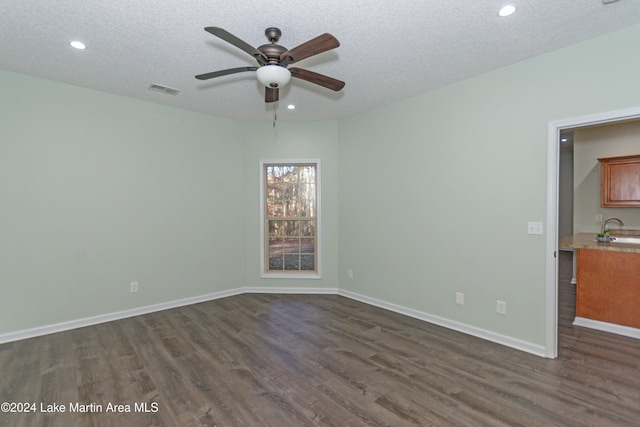 empty room featuring a textured ceiling, ceiling fan, dark hardwood / wood-style flooring, and sink