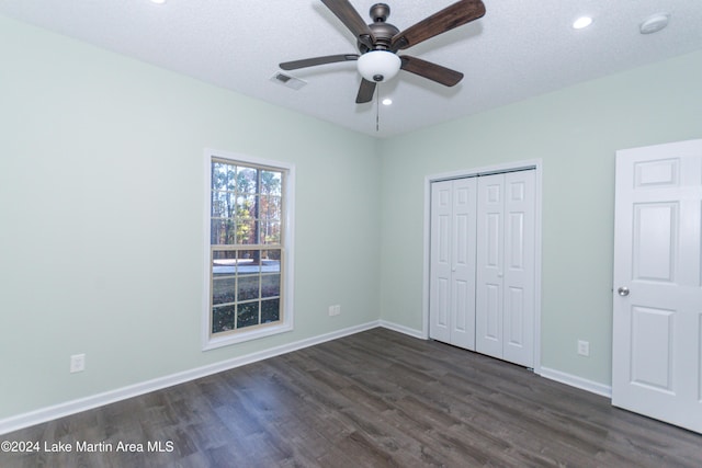 unfurnished bedroom featuring a textured ceiling, ceiling fan, a closet, and dark hardwood / wood-style floors