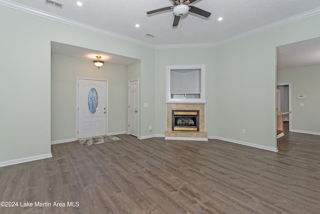 unfurnished living room with a tiled fireplace, dark hardwood / wood-style floors, a textured ceiling, and ornamental molding