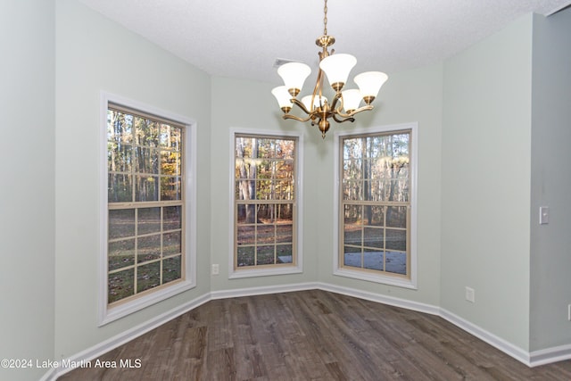 unfurnished dining area featuring dark hardwood / wood-style flooring, a textured ceiling, and a chandelier