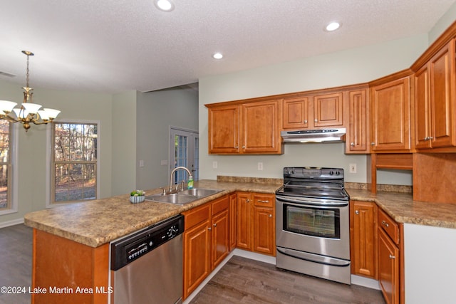 kitchen with sink, dark hardwood / wood-style floors, a notable chandelier, kitchen peninsula, and appliances with stainless steel finishes