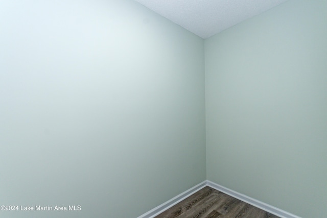 unfurnished room featuring a textured ceiling and dark hardwood / wood-style floors