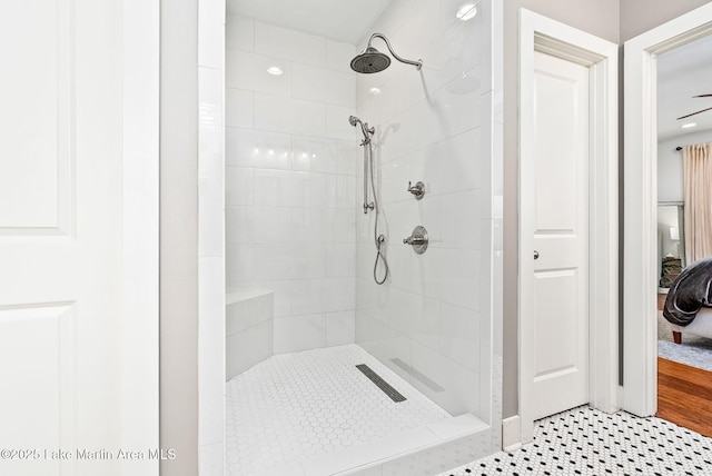 bathroom featuring a tile shower and ceiling fan