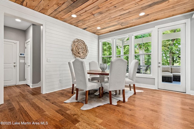 dining room with hardwood / wood-style flooring, wood walls, and wood ceiling