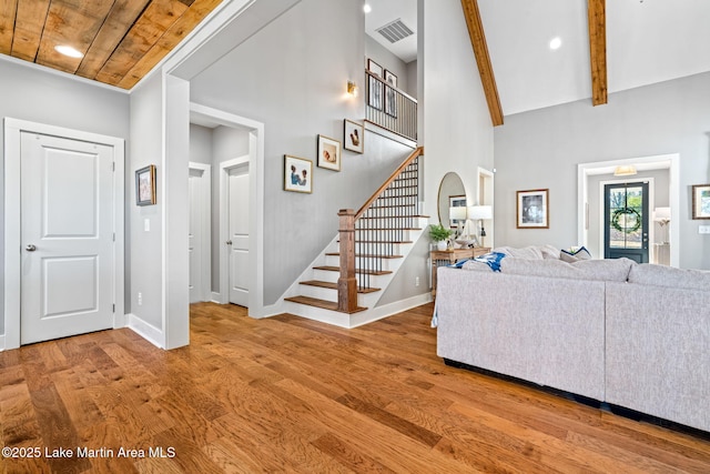 living room featuring hardwood / wood-style floors, a towering ceiling, wooden ceiling, and beam ceiling